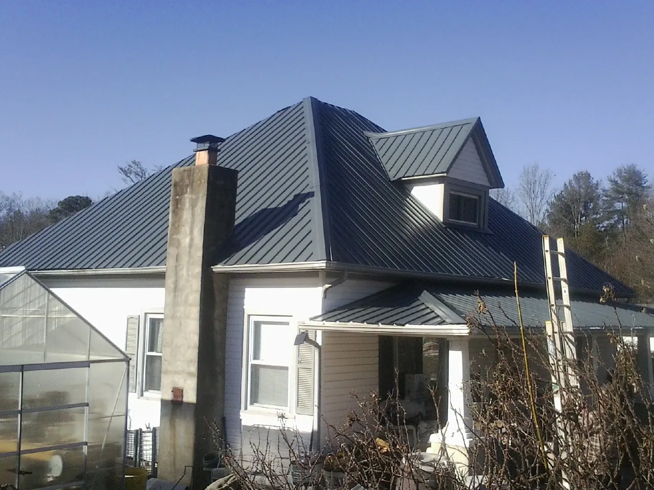 Dark blue standing seam metal roof on a white farmhouse with dormer — Slate & Tile Roof Repair by Roofing Brothers in Centre Hall