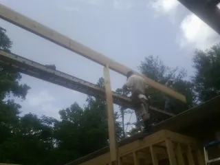 Carpenter setting a ridge beam over a new addition frame — Ice Dam Removal by Roofing Brothers in Centre Hall