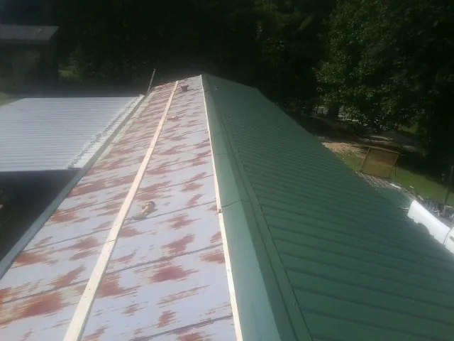 Old rusted panels beside newly installed green metal roofing — Wind Damage Roof Repair by Roofing Brothers in Centre Hall