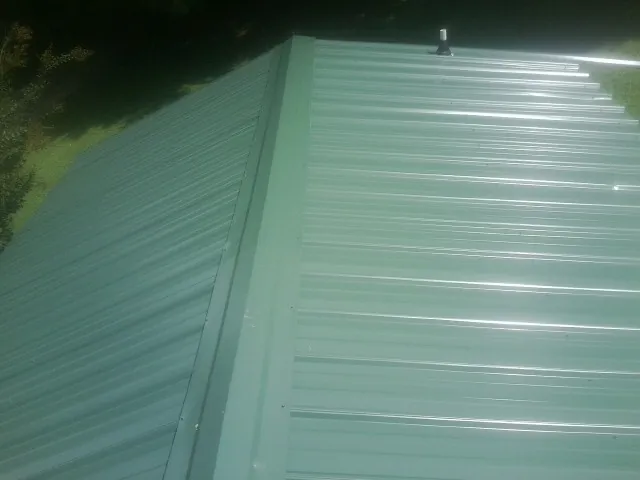 New green metal panels meeting at the ridge of a roof — Flat Roof Repair work by our crew in Centre Hall