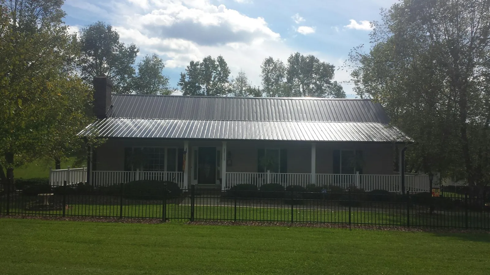 Gray metal roof on a brick ranch with a full width front porch — Gutter Guard Installation work by our crew in Centre Hall