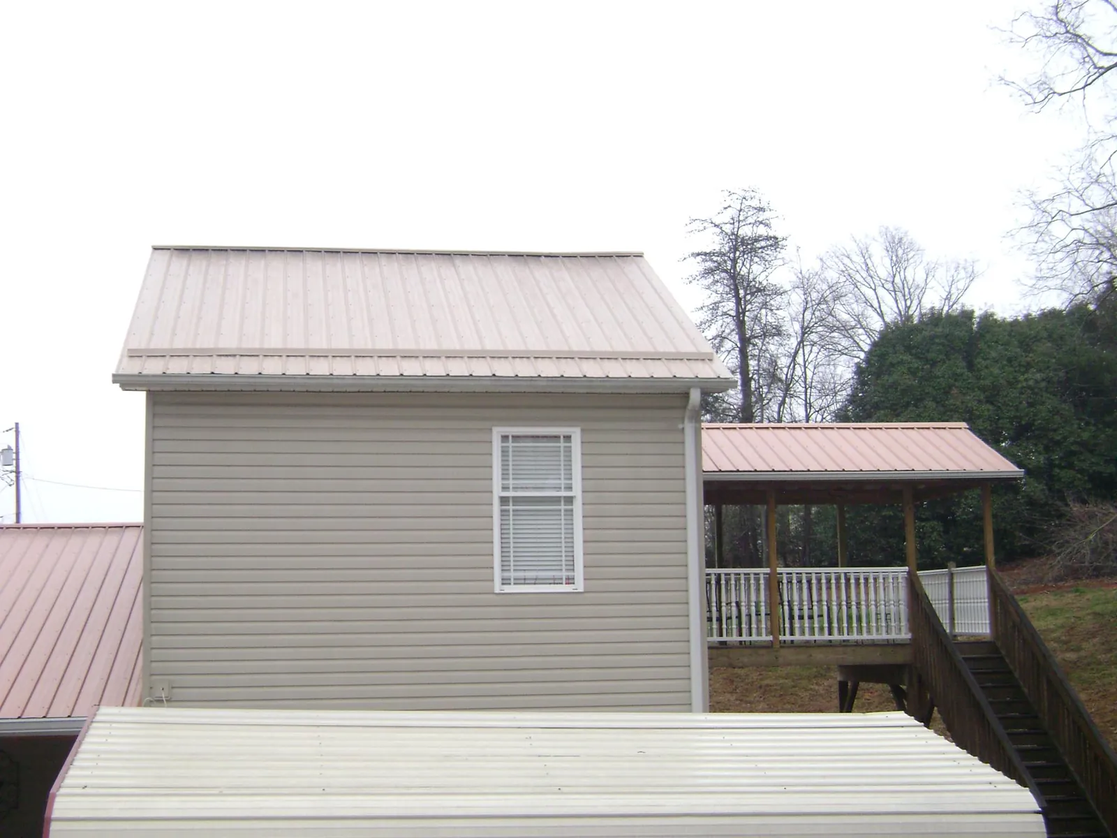 Tan metal roofs on a two story addition and attached porch, from a Roof Replacement job in Centre Hall