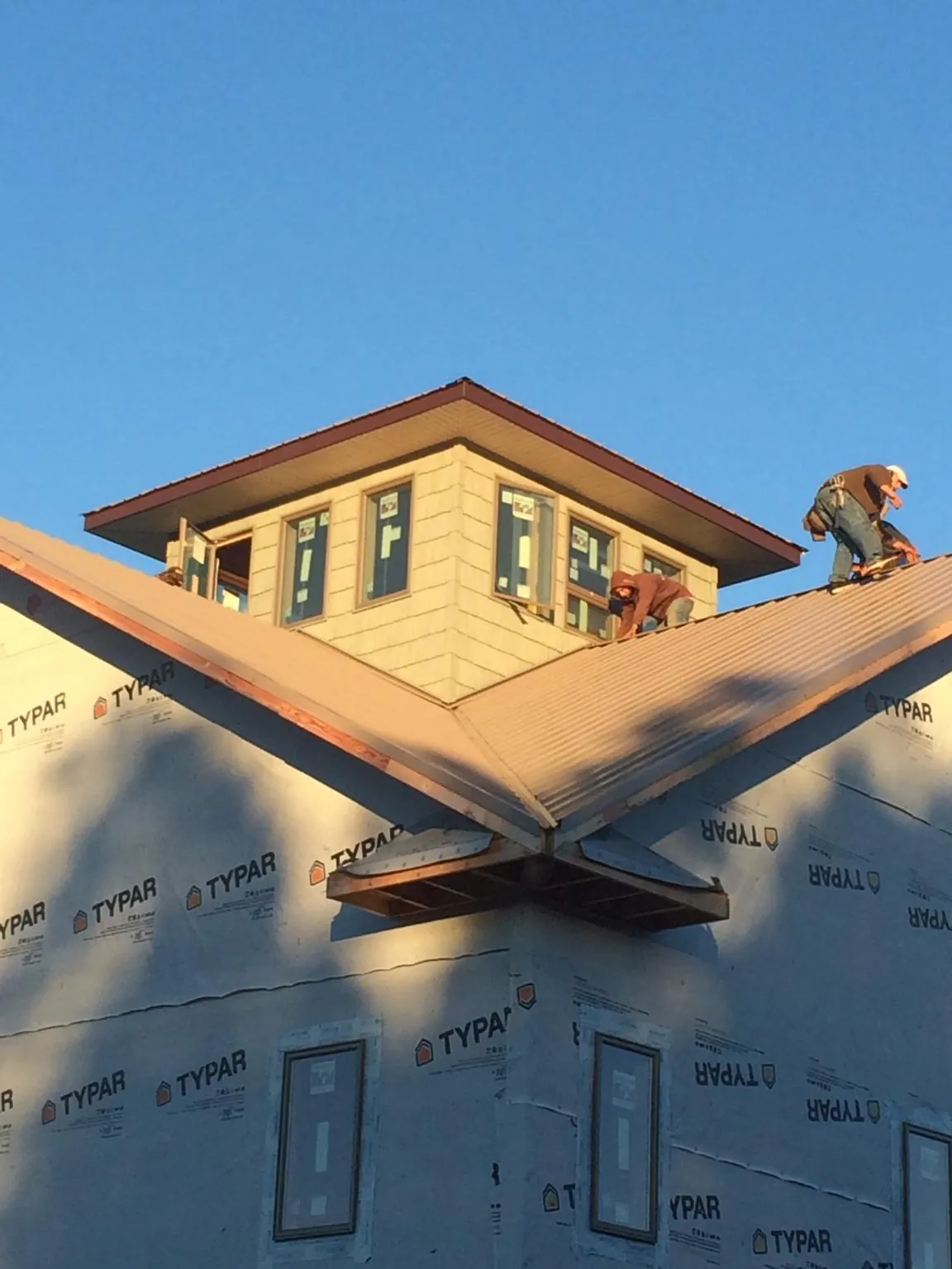 Roofers working around a rooftop cupola on a new metal roof at sunset — Roof Waterproofing in Centre Hall by Roofing Brothers